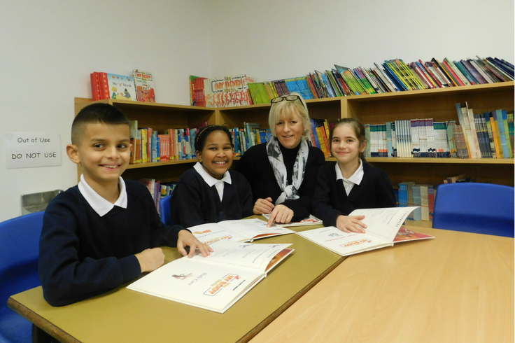 A teacher and three school children. Each of them have a textbook.